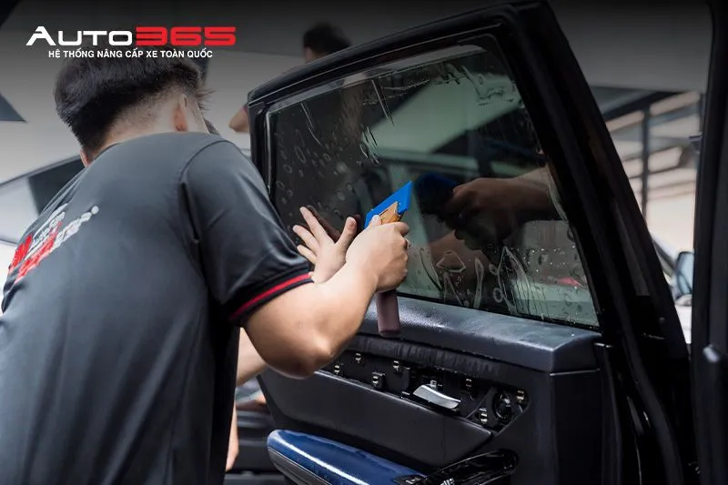 Kỹ thuật viên Auto365 thao  tác dán phim trên kính sườn  ô tô