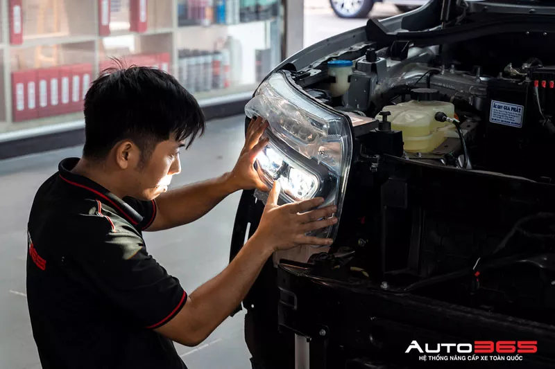 Kỹ thuật viên kiểm tra bề mặt mặt đèn pha để đánh giá xước mờ ố vàng hoặc rạn