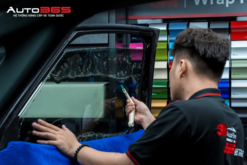 Kỹ thuật viên thi công phim ở kính sườn trước Toyota Alphard; mã CR BLK 35 được đối chiếu theo hồ sơ