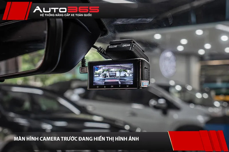 Màn hình camera trước đang hiển thị hình ảnh, cạnh gương chiếu hậu trong cabin
