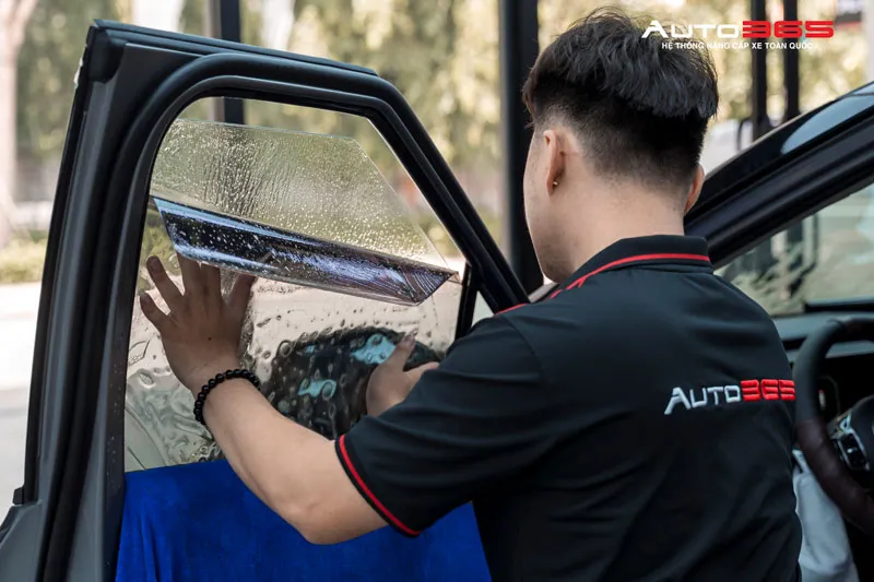 Kỹ thuật viên thực hiện dán kính sườn trong quy trình thi công phim cách nhiệt 3M Kia Carnival
