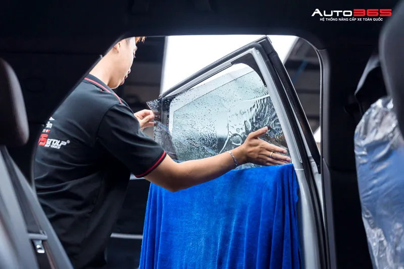 Kỹ thuật viên đang thực hiện dán phim cách nhiệt 3M lên kính cửa ô tô. 
