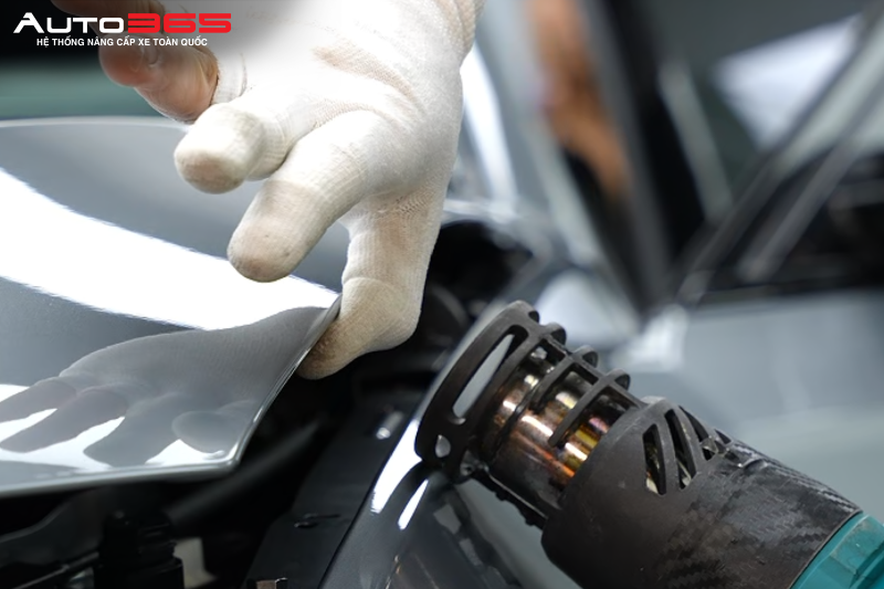Kỹ thuật viên xử lý khu vực mép phim trên BMW 330i trong quá trình hoàn thiện trước khi bàn giao